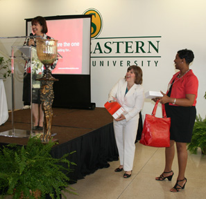 Emcee Rosa Dunn, Alexis Ducorbier, and Sandy Summers draw for the main doorprize -- a Dooney and Bourke cherry red purse and wallet provided by Ducorbier.
