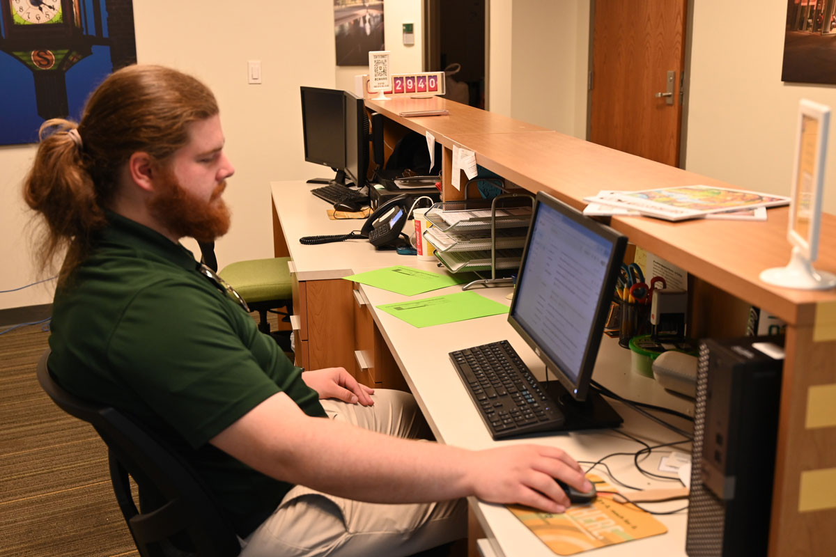 Student worker working on the computer at his desk at Campus Tours at Southeastern.