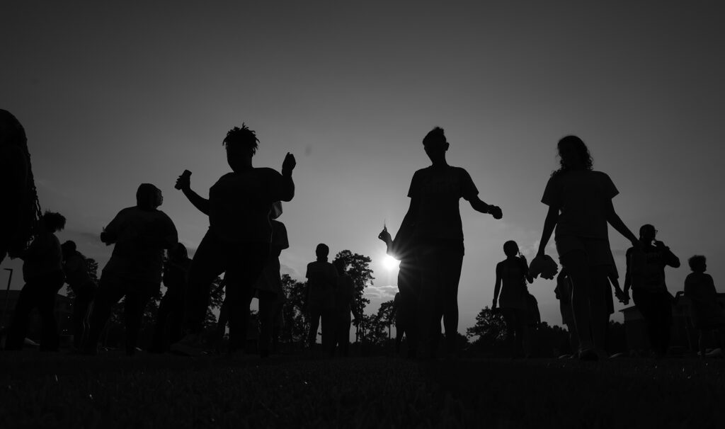 Students stand outside with a sunset in the background.