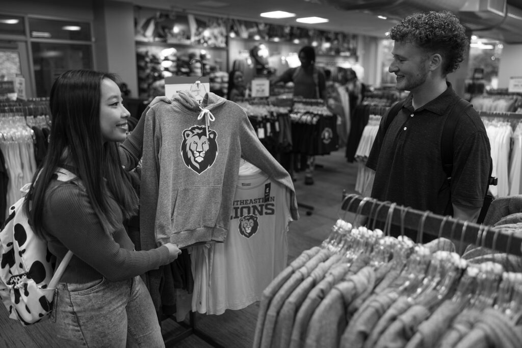 A female and male student look at a sweatshirt featuring Southeastern's new spirit logo in 2022.