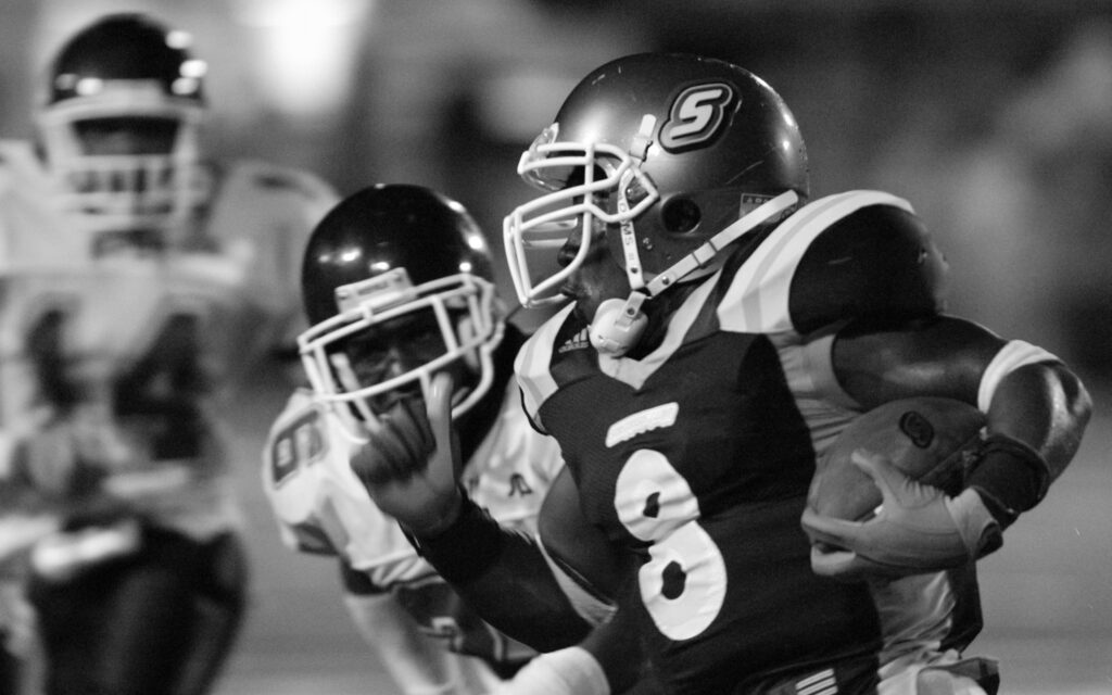 A Lions football player runs with the ball in 2003.