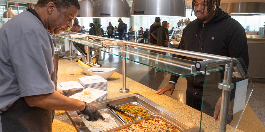 Student being served food in The Mane Dish.