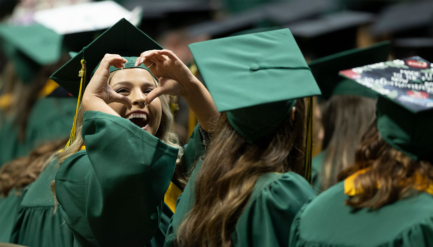 Southeastern graduate making a heart with her hands