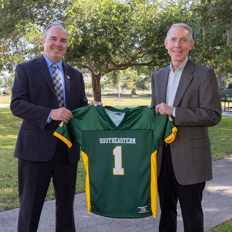 Dr. Wainwright and Dr. Crain holding a Southeastern football jersey.