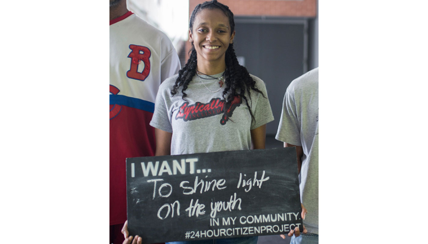 alex johnson holding sign that says I want...to shine light on the yout in my community #24hourcitizenproject