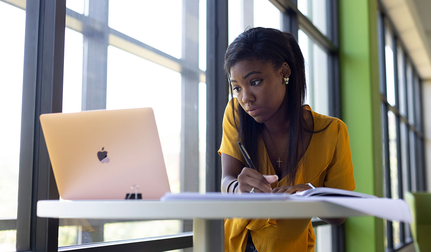 girl at a desk looking at mac laptop