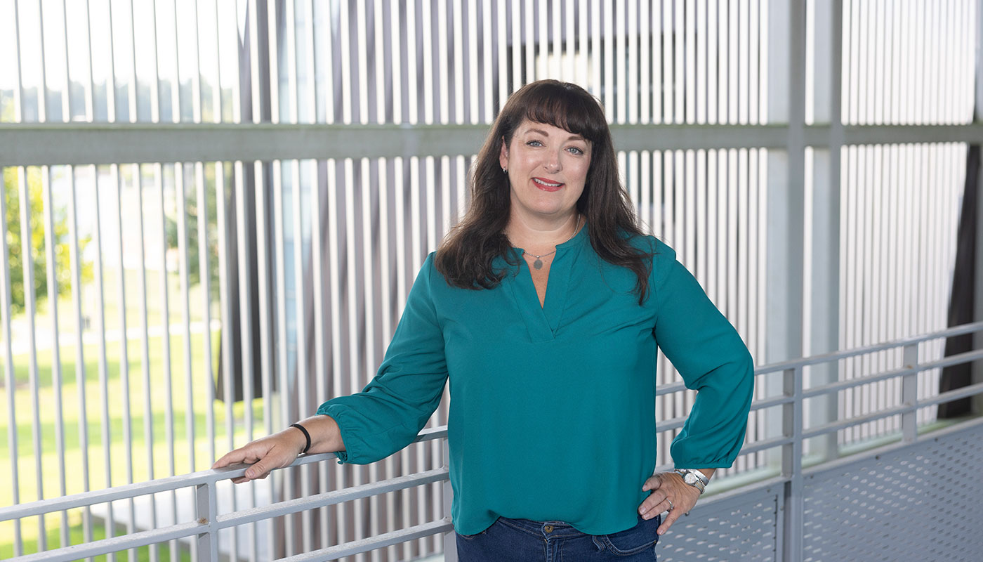 A nursing student stands on the Nursing building walkway