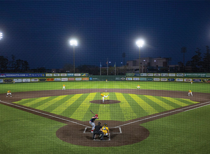 Baseball being played at Alumni Field at night.
