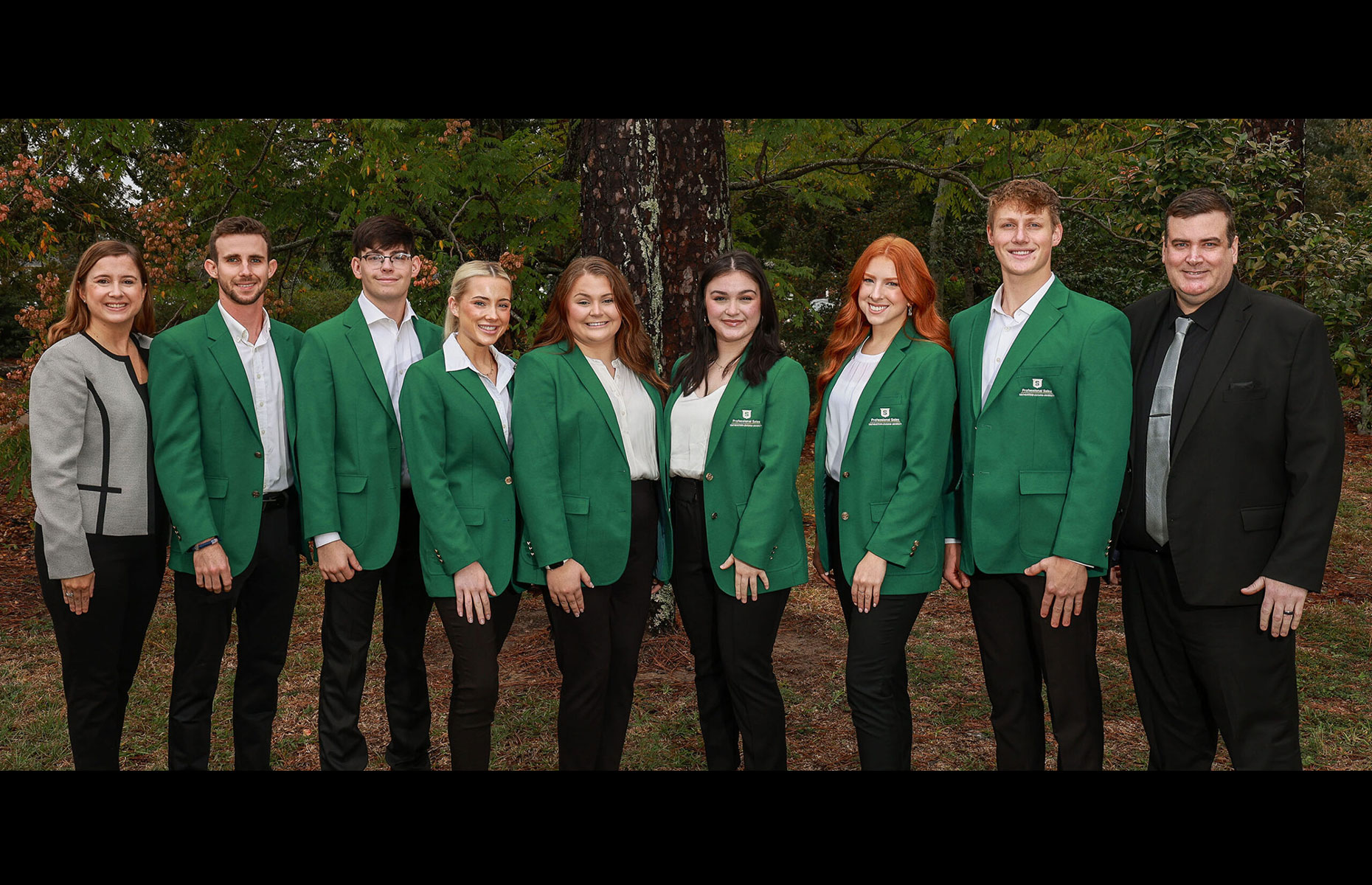 Photo of business students posing in green jackets.